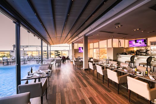 Spacious modern restaurant interior with a poolside view, featuring elegant furniture and contemporary design.
